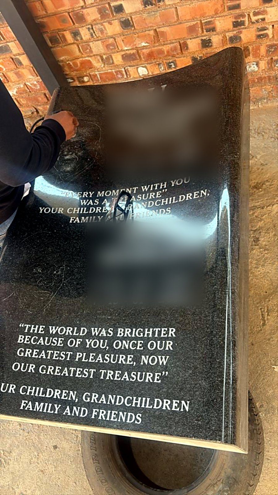 An artist hand-etching a portrait into a polished black granite headstone